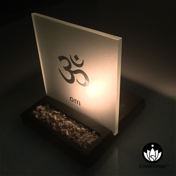 Frosted Glass Tealight Candle Holder with Om Symbol lit up at night with a burning candle